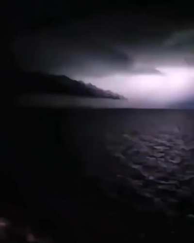 ? Thunder lights up the sky, revealing the shape of something immense.