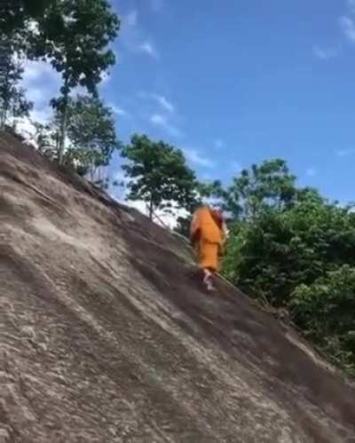 Monk climbs a steep hill with no ropes