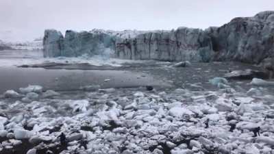 Tourists watch and scramble for cover as a huge chunk of the Breiðamerkurjökull glacier calves. The scale is hard to imagine until you see the waves.