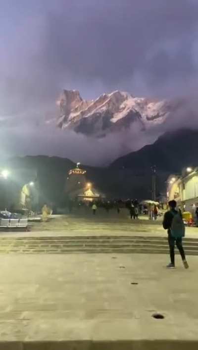 Early morning view of Kedarnath temple, India estimated to be built in 726 AD. On ground it's still Dark and street lights are on; high up above, sunlight bathing the glaciers.