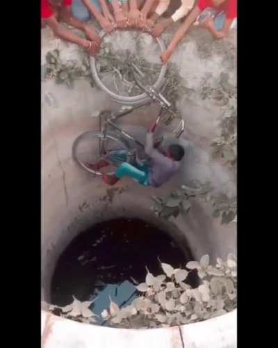 Kids in India pulling out a football that fell in a well.