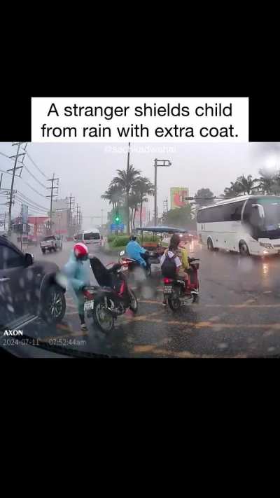 A stranger shields child from the rain.