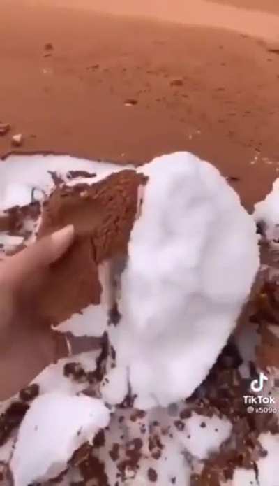 Snowfall sandwiched between layers of sand in Tabuk, Saudi Arabia