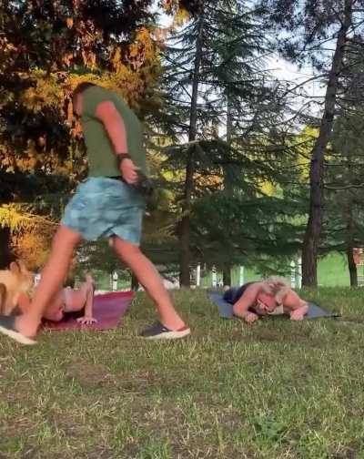 Man trying to control his dog around two girls doing yoga