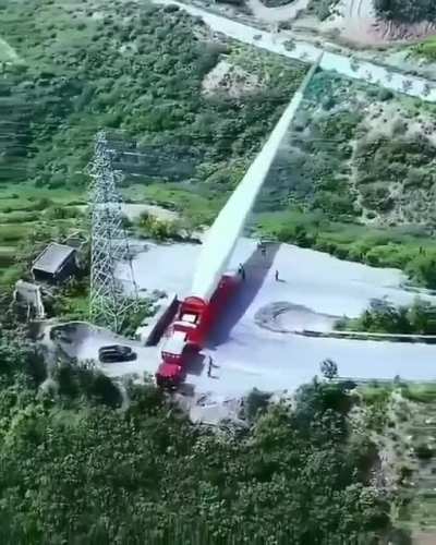 Transporting a massive turbine blade up a winding mountain road.