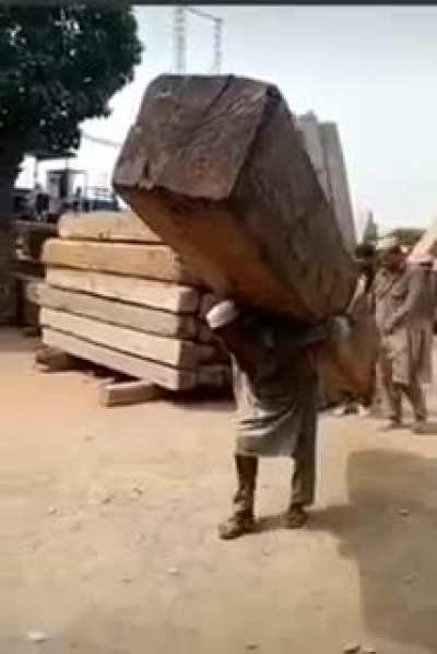 Man single Handedly carries massive wooden pillar