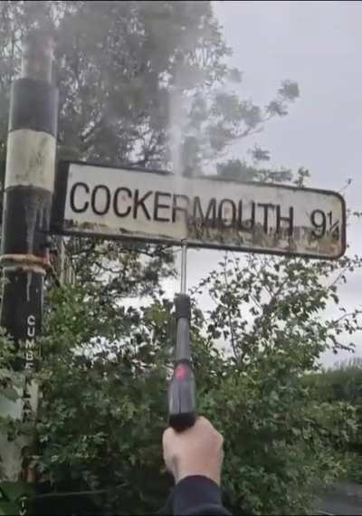 Pressure washing a road sign of an English town