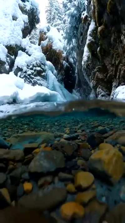 ? Snow falling on crystal clear Alaskan glacial melt water captured by photographer John Derting.