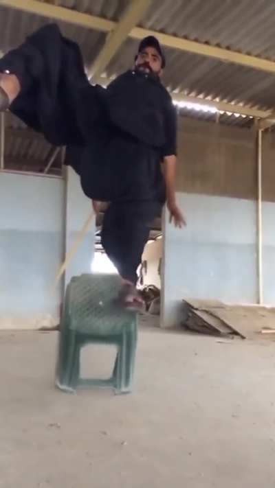 Using a flimsy plastic stool as stable grounding for a boost jump, while holding a stick in your hand, and baggy trousers.