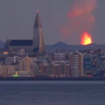 ?Iceland town with a Volcano erupting in the background