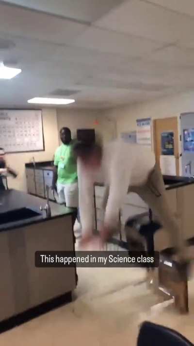 Person jumping onto a school desk in a science laboratory.