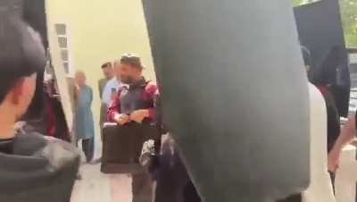 Security personnel use a bulletproof shield to protect former Pakistan prime minister