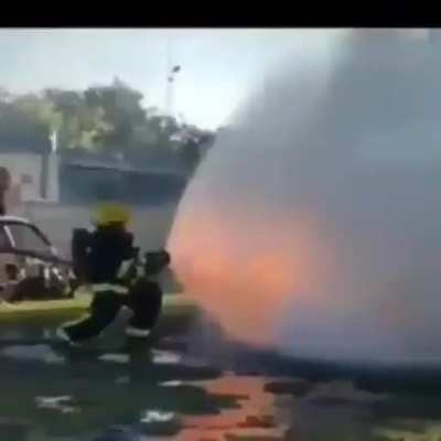 This fireman in a training demonstration using a wide angle cone shaped spray to fight back a flame