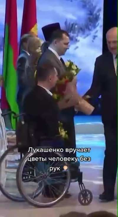 "The President of Belarus presents a bouquet of flowers to an armless man"