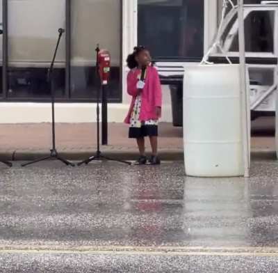 Little girl singing in the rain at a Juneteenth celebration in front of the Rosa Parks Museum in Montgomery, AL.