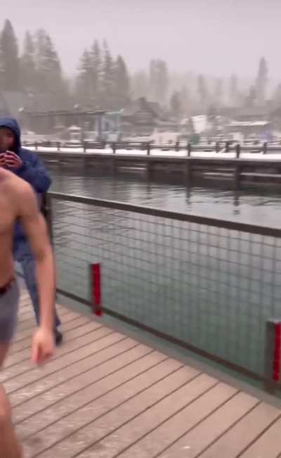 Guy tries to jump over a barrier into the water in the snow