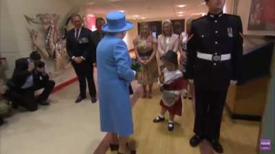 A little girl gives flowers to the queen