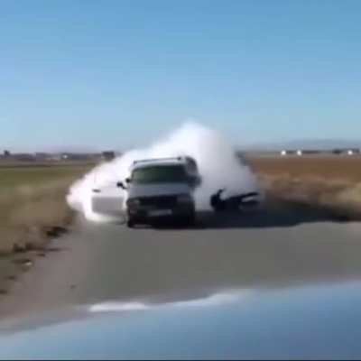 A guy tries to shoots an “RPG” in the back of a car, but it back fires... ( it doesn’t look like an rpg but idk)