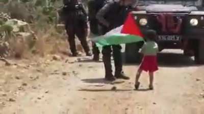 A man telling his child to throw rocks at a soldier, but he instead gets a high five from the soldier