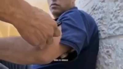 Calmly opening a cut in the arm of his t-shirt