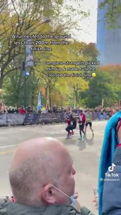 Two strangers assist a fellow runner at the NYC marathon