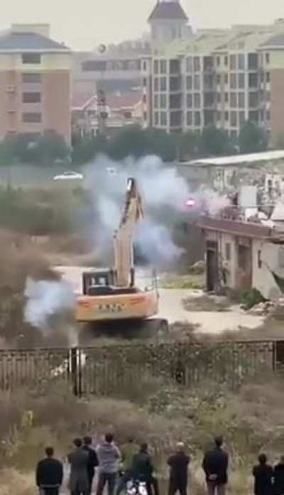 Chinese man fights off excavator that came to demolish his house with fireworks .