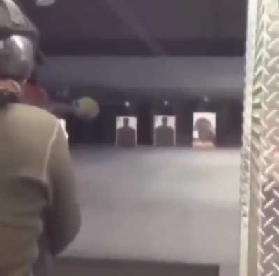 Guy fires RPG at an indoor firing range, with someone behind him