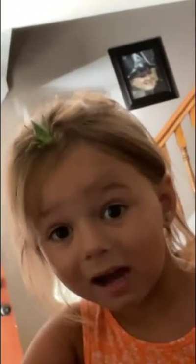Little girl is unaware of the cricket on her head.