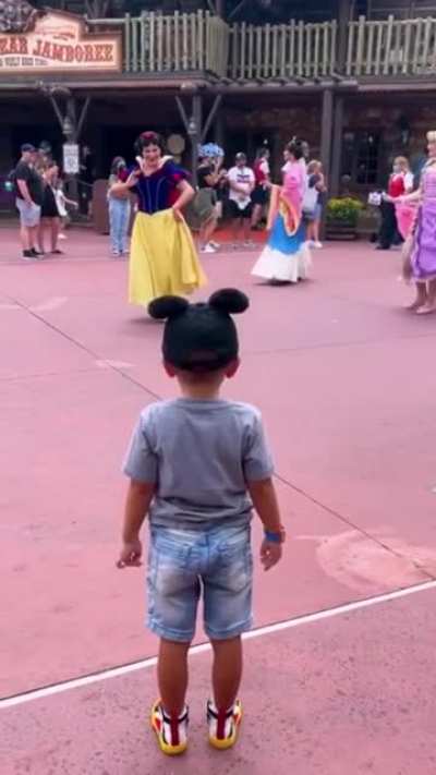Little boy tipping his hat to Disney princesses.