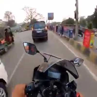 Two guys race through the streets of India