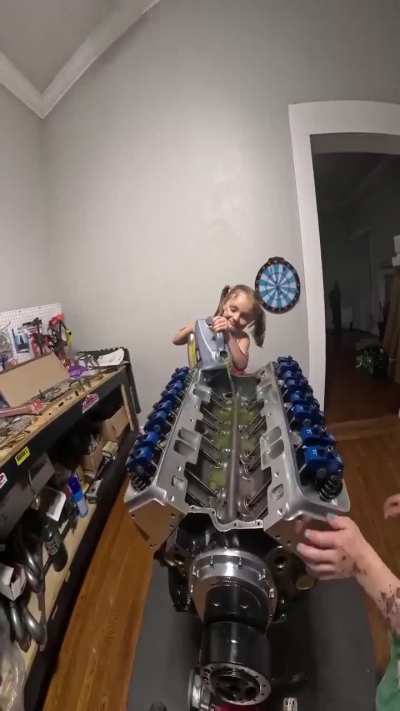 Two little girls helping their dad build an engine?